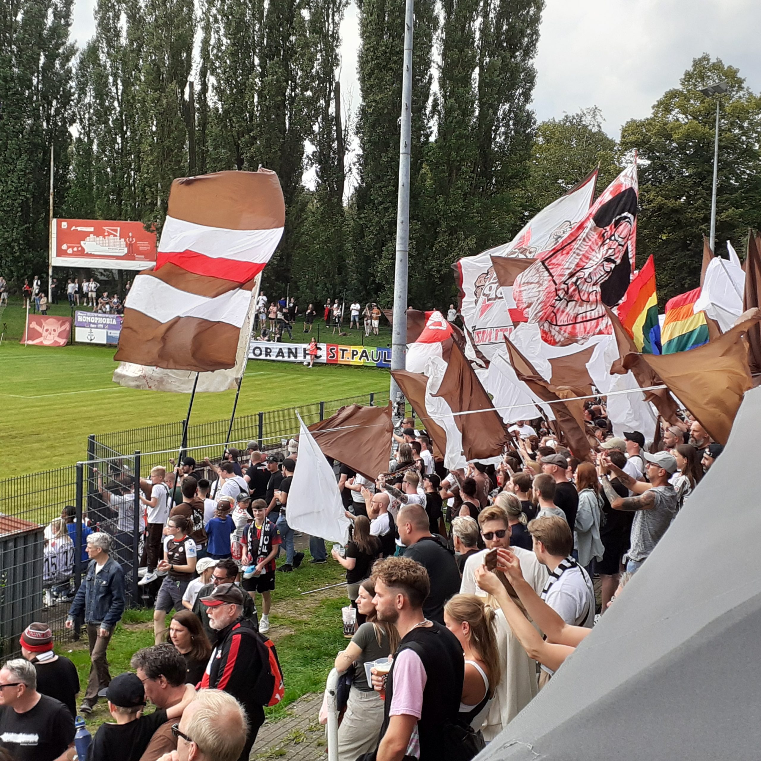 St.Pauli-Heimspielatmosphäre an der Adolf-Jäger-Kampfbahn: Viele St. Pauli Fans mit braun-weißen sowie bunten Fahnen und Bannern auf den Rängen.