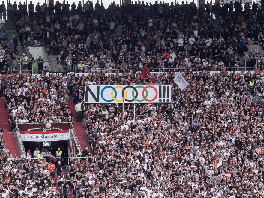 Ein Banner mit "NOOOOO!!!" (die Kreise überlappen sich wie die Olympiaringe und haben auch deren Farben) in der Gegengerade.