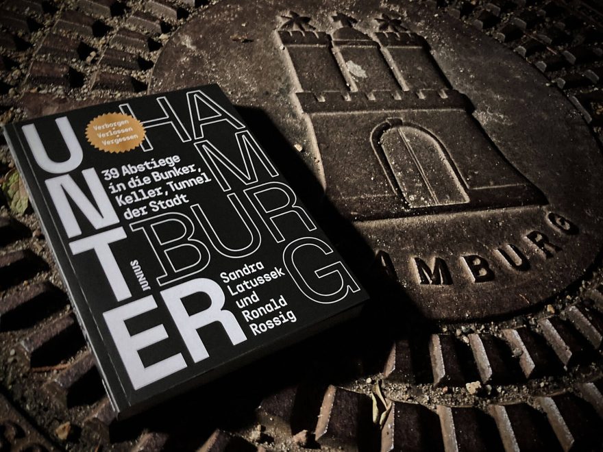 Das Buch "Unter Hamburg" pletziert neben einem Hamburger Gullideckel.